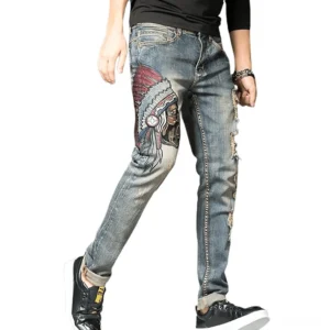 Men's gothic embroidered ripped denim jeans in vintage blue, slim fit pencil cut, side profile view showcasing thigh embroidery and distressed details