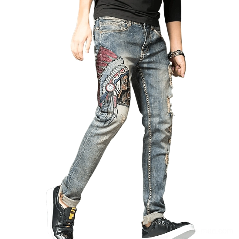 Men's gothic embroidered ripped denim jeans in vintage blue, slim fit pencil cut, side profile view showcasing thigh embroidery and distressed details