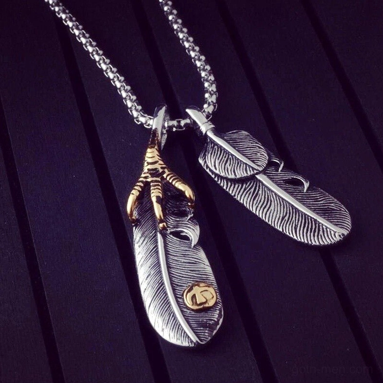 Gold-tone claw with dual-feather pendant necklace on dark wood grain background, showing vintage craftsmanship details
