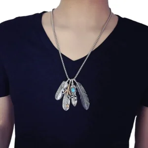 Male model wearing gothic feather claw pendant necklace with silver finish and turquoise inlay, styled with casual indoor outfit