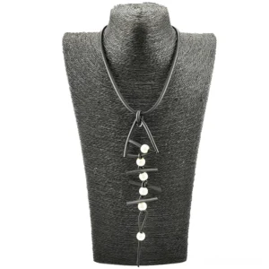 Dark gothic fish bone pendant long necklace displayed on textured black mannequin with white pearl details