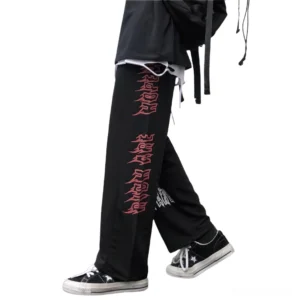Gothic trousers side profile with red flame prints and white cross design, worn with black sneakers