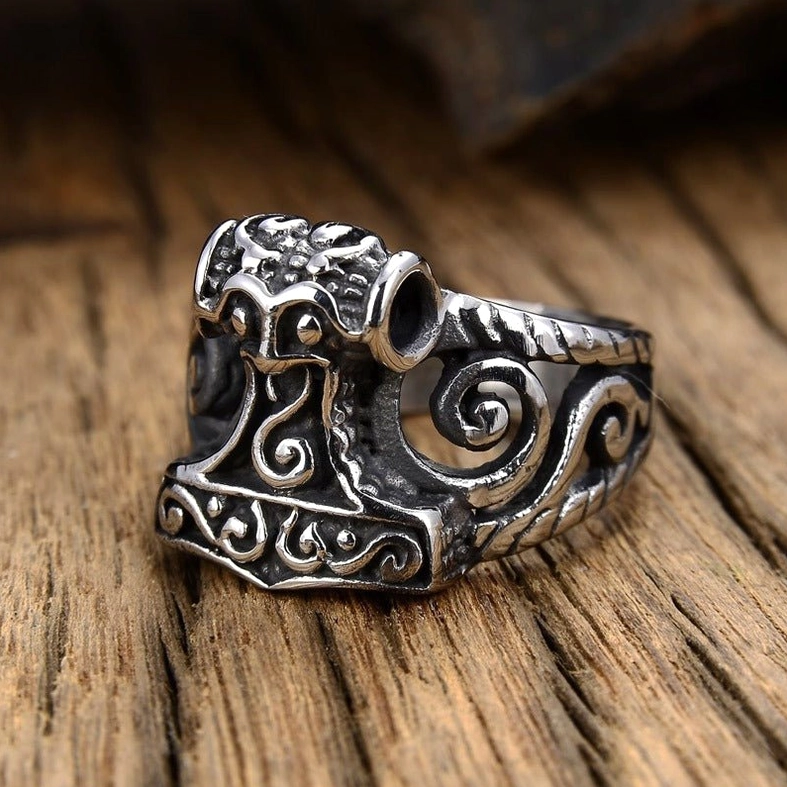Gothic Thor's Hammer ring side-front view on wooden desktop showing hollow scroll design and rope texture detail on band