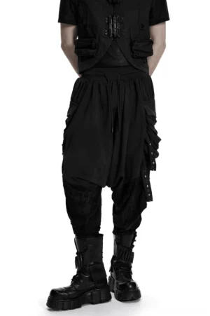 Black gothic drop-crotch harem pants with studded cargo pockets, front three-quarter view on male model wearing combat boots