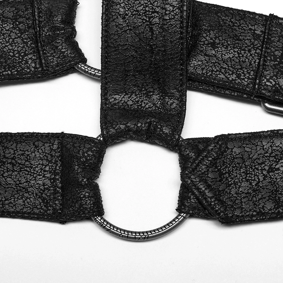 Close-up studio shot of textured black faux leather harness strap with metal o-ring joint and stitched seam edges
