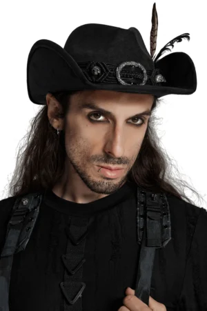 Black gothic cowboy hat with horns and feather detail worn by long-haired male model, front close-up view featuring braided band and skull buckles