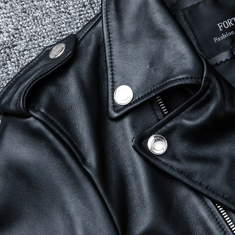 Close-up of black leather jacket shoulder panel with silver snap fasteners and fine grain leather surface