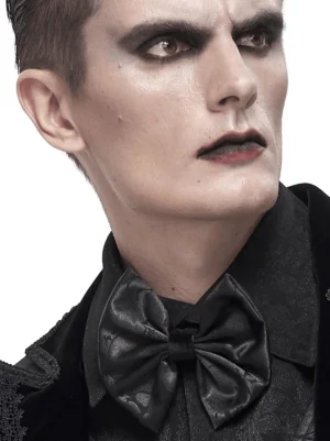Male model wearing black jacquard gothic bow tie with lace-up design on formal black shirt, three-quarter studio portrait view
