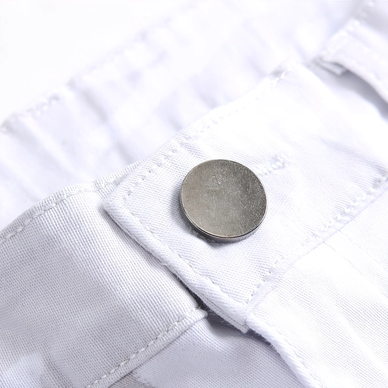 Extreme close-up of antique brass button fastening and silver hardware on white denim waistband