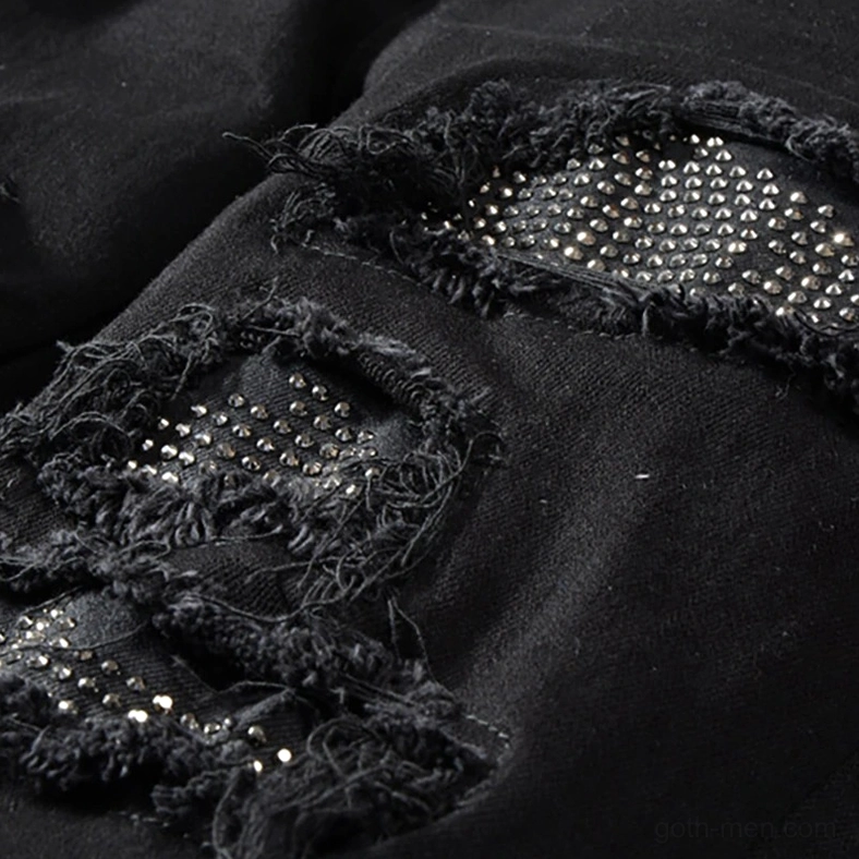 Distressed rip hole with embedded rhinestones showing gothic punk aesthetic detail and frayed edges