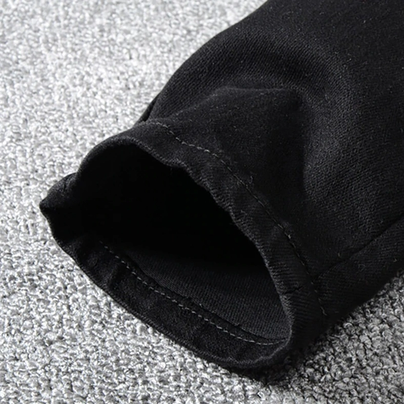 Jean hem cuff and tapered ankle finish on black gothic distressed slim fit jeans