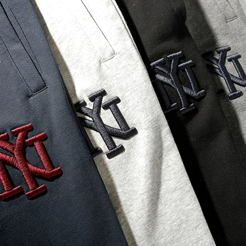 Close-up detail of NY embroidery logo on gothic jogger sweatpants, showing embroidered design variations