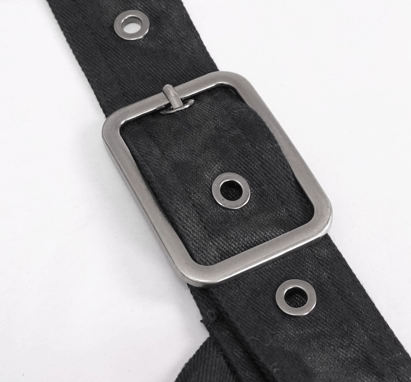 Close-up detail of silver rectangular buckle, leather belt strap, and metal eyelets on gothic kilt