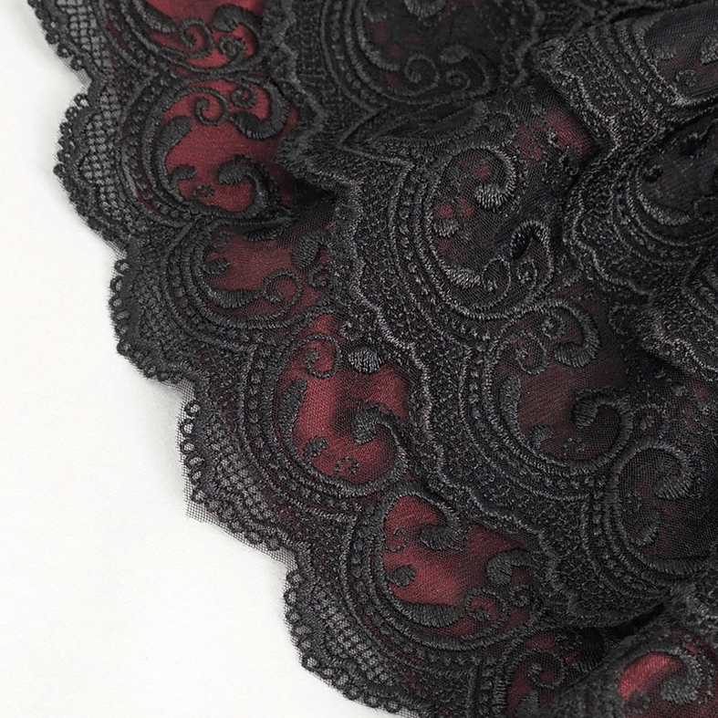 Macro close-up of black paisley embroidered lace with scalloped edge and wine red lining on gothic cravat