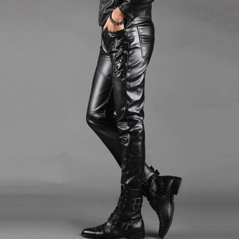 Men's black faux leather pants side view showing lace-up details and tapered silhouette with crossed leg pose