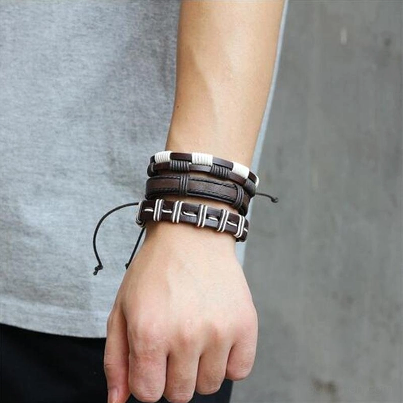Multi-layer gothic leather wristbands stacked on wrist, close-up side view displaying three braided bracelets with white stripe details and adjustable cords