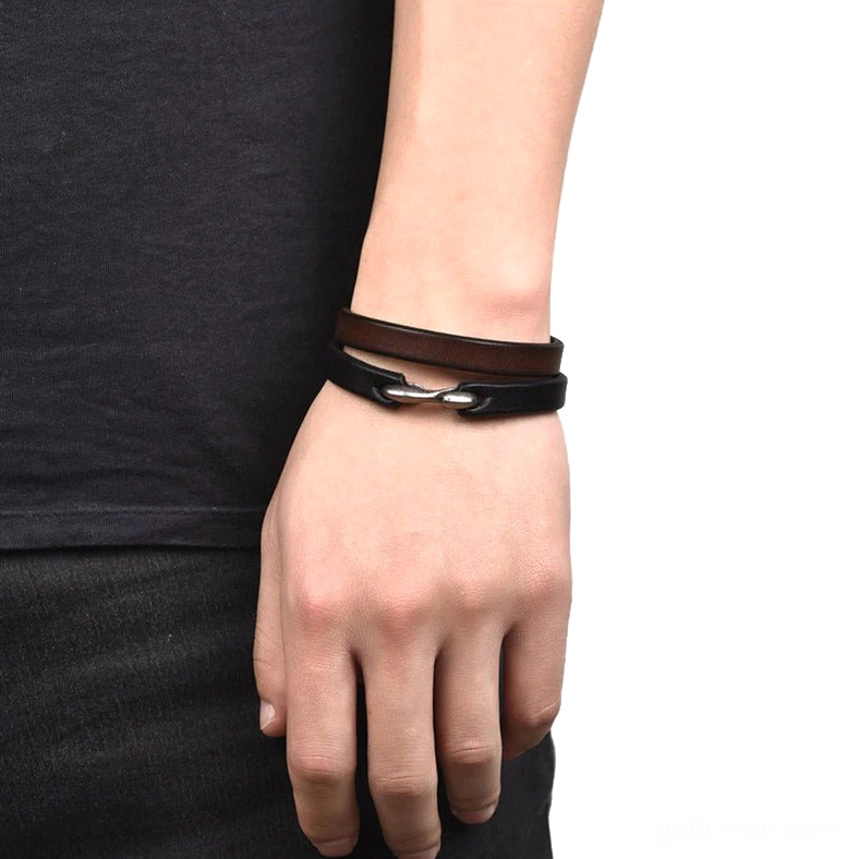 Male model wearing dual gothic leather bracelets, black and brown cuff bracelets on wrist with boat hook clasps