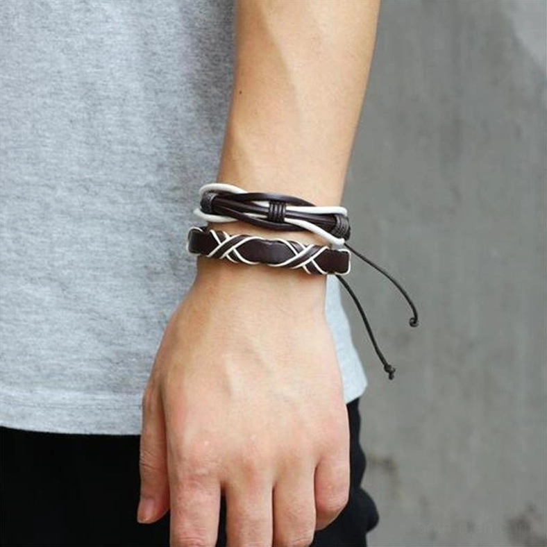 Gothic leather bracelet set worn on male wrist, close-up side angle showing two layered brown and white bracelets with pull-tie adjustment