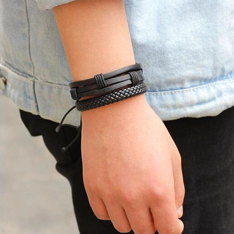Men wearing braided black leather gothic bracelet on wrist denim jacket side view