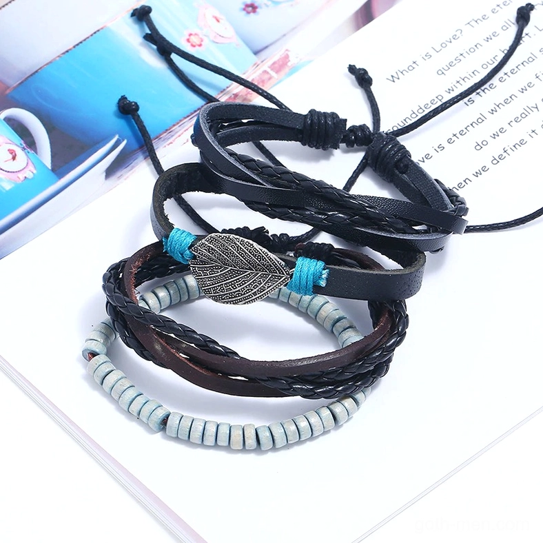 Stacked gothic leather bracelets in black and brown leather with natural wooden beads on stationery background
