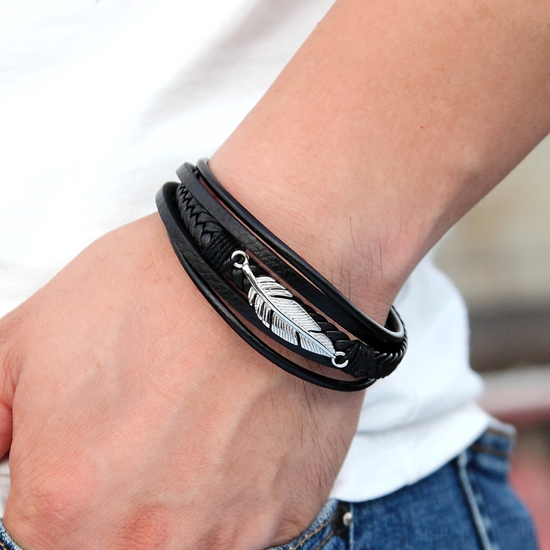 Silver feather charm leather bracelet worn on human wrist, close-up everyday wear shot on casual background