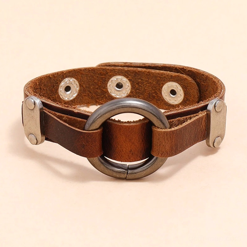 Flatlay gothic leather cuff bracelet topdown view displaying brown distressed leather, round alloy ring center, and silver rivet buckle fasteners