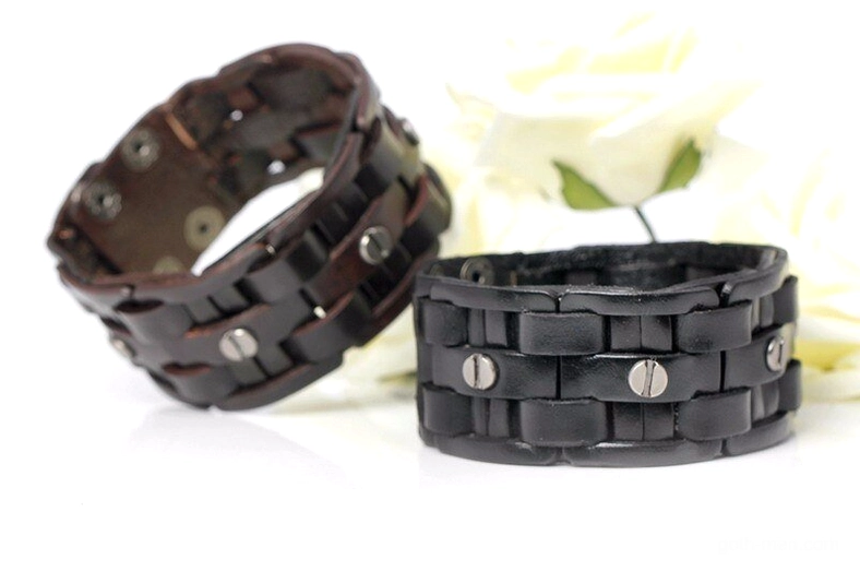 Pair of hand-woven leather gothic cuff bracelets with metal rivets and snap closures, mixed angle view on white flower background