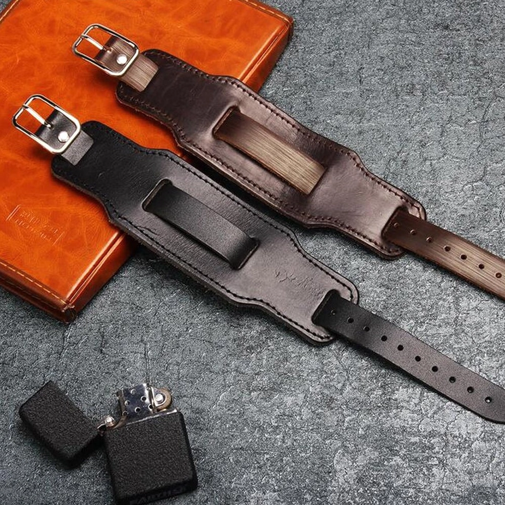 Black and brown genuine leather gothic cuff bracelets styled with leather notebook and lighter on dark background lifestyle setup