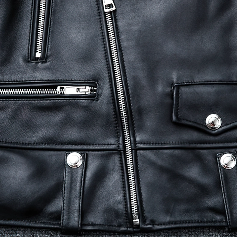 Lower front section of black sheepskin leather jacket showing asymmetrical main zipper and snap button pocket
