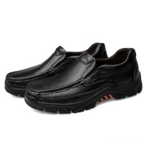 Pair of black gothic slip-on leather loafers with perforated toe cap and orange sole accents, front three-quarter view