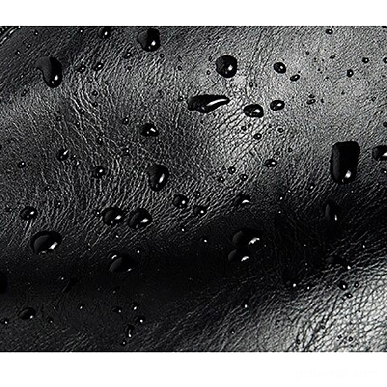 Vintage black leather material texture showing water-resistant grain pattern and water droplets