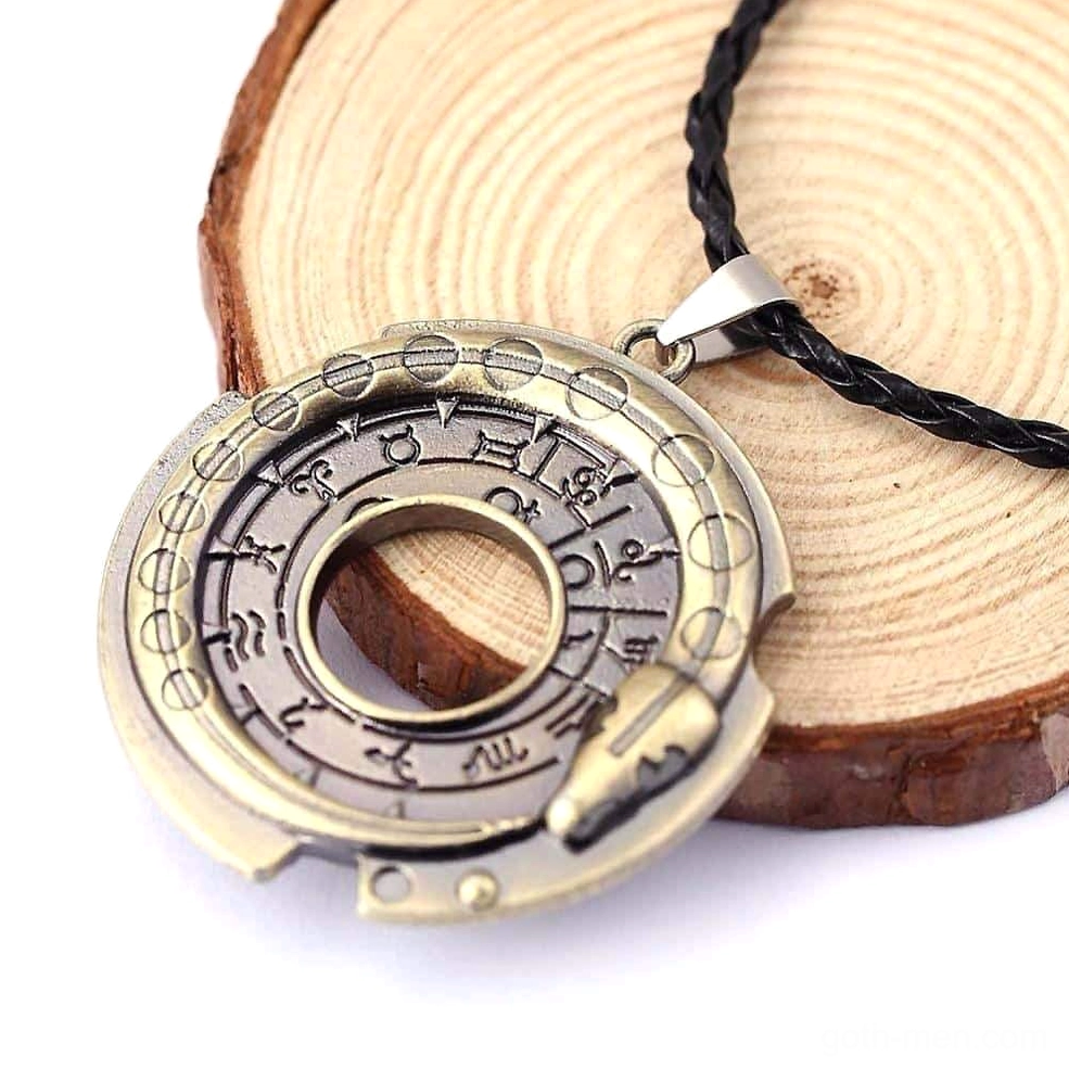 Gothic serpent pendant necklace displayed on wooden coaster, showcasing intricate zodiac symbols and snake decoration with bronze-toned metal details