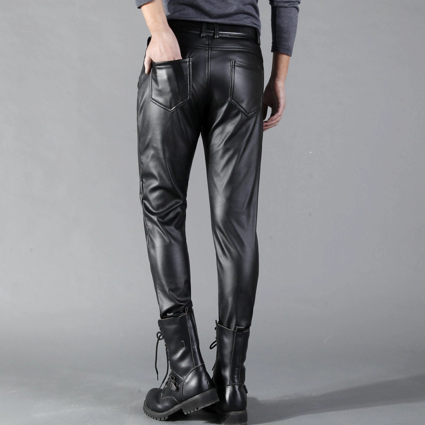 Men's black skinny gothic leather pants rear full view, hand positioned in back pocket, paired with combat boots and dark styling