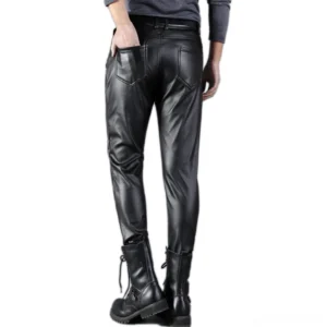 Men's black goth leather pants rear view, male model shown from behind with back pockets, styled with combat boots and alternative fashion accessories