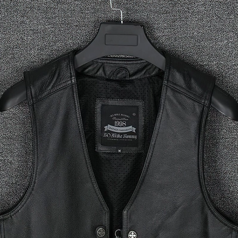 Black genuine leather gothic waistcoat displayed on hanger, front view showing metal snap fasteners, grain leather texture, and collarless design
