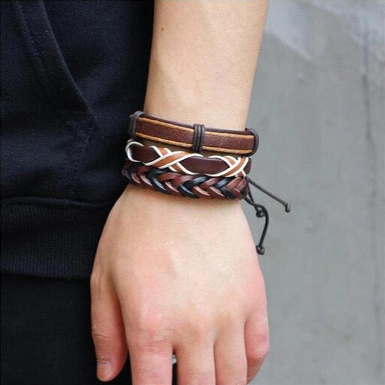 Male wrist displaying gothic dual stacked leather bracelets with cross woven and smooth leather styles on side close-up