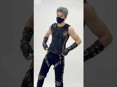 Side three-quarter view of male model in gothic sleeveless top with visible mesh side panels and buckle strap details