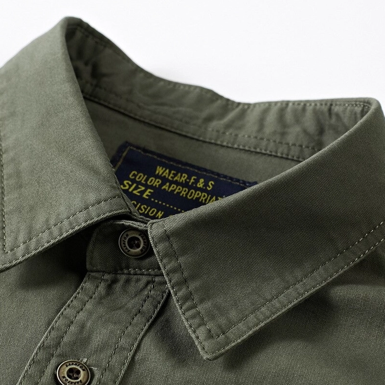 Detailed close-up of olive green chest flap pocket with off-road embroidery and metal button hardware