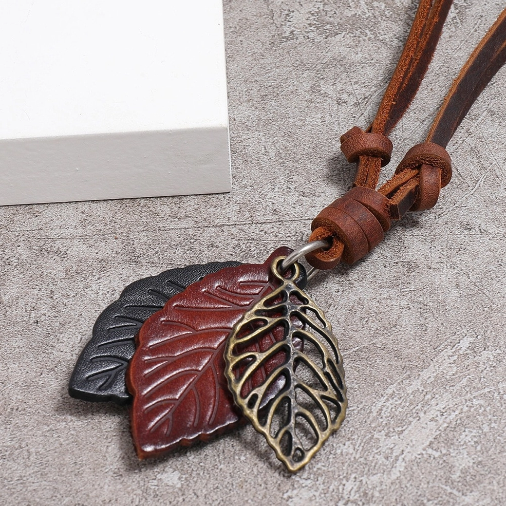 Close-up of bronze hollow alloy leaf pendant on dark brown and black vintage leather necklace - side detail