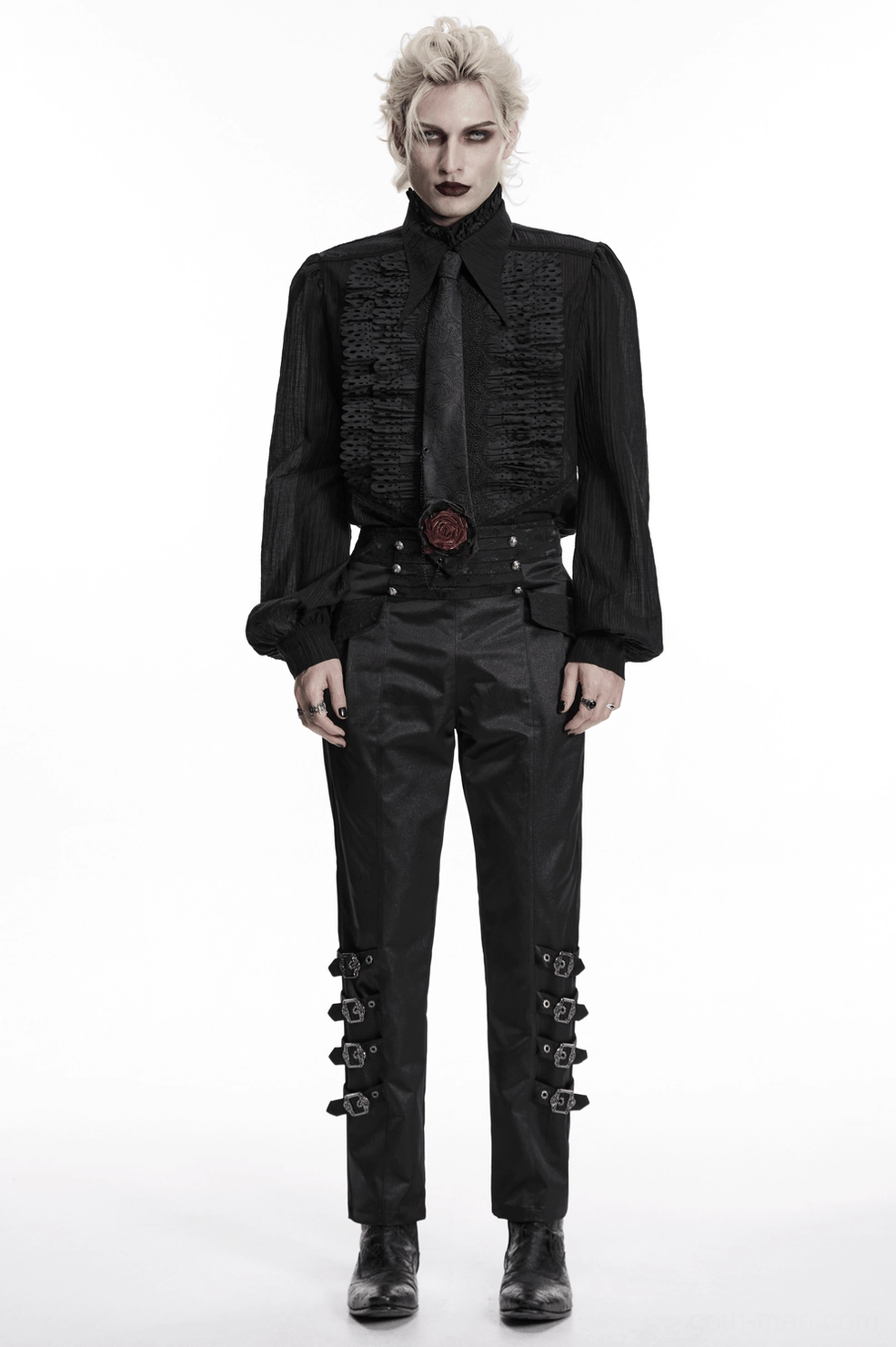 Blonde androgynous model wearing complete gothic formal outfit featuring black paisley necktie, ruffled black shirt, studded trousers, and matching goth shoes