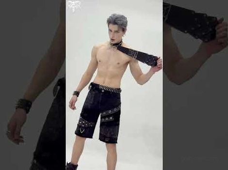 Full body side view of male model wearing gothic spider web necktie with matching studded accessories and wrist bracelet