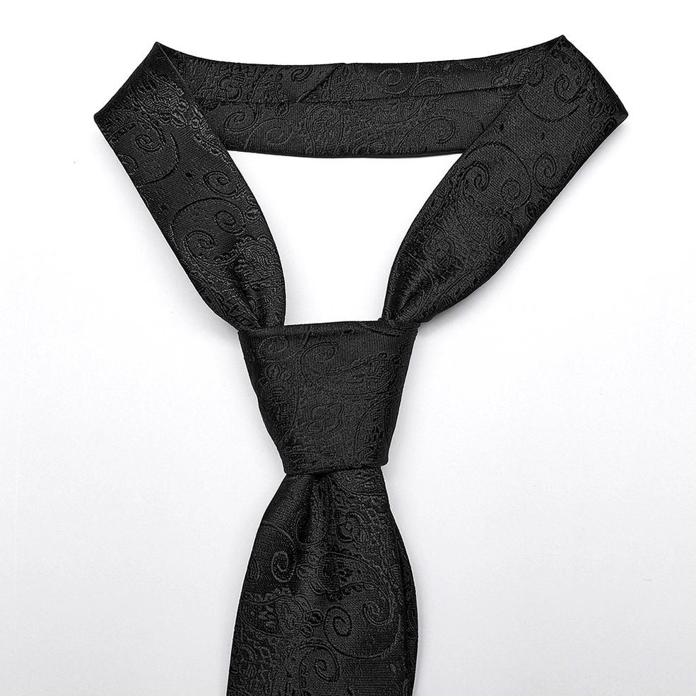 Pre-tied black gothic necktie front flat lay showing neat knot and paisley jacquard weave pattern with cross stud embellishments