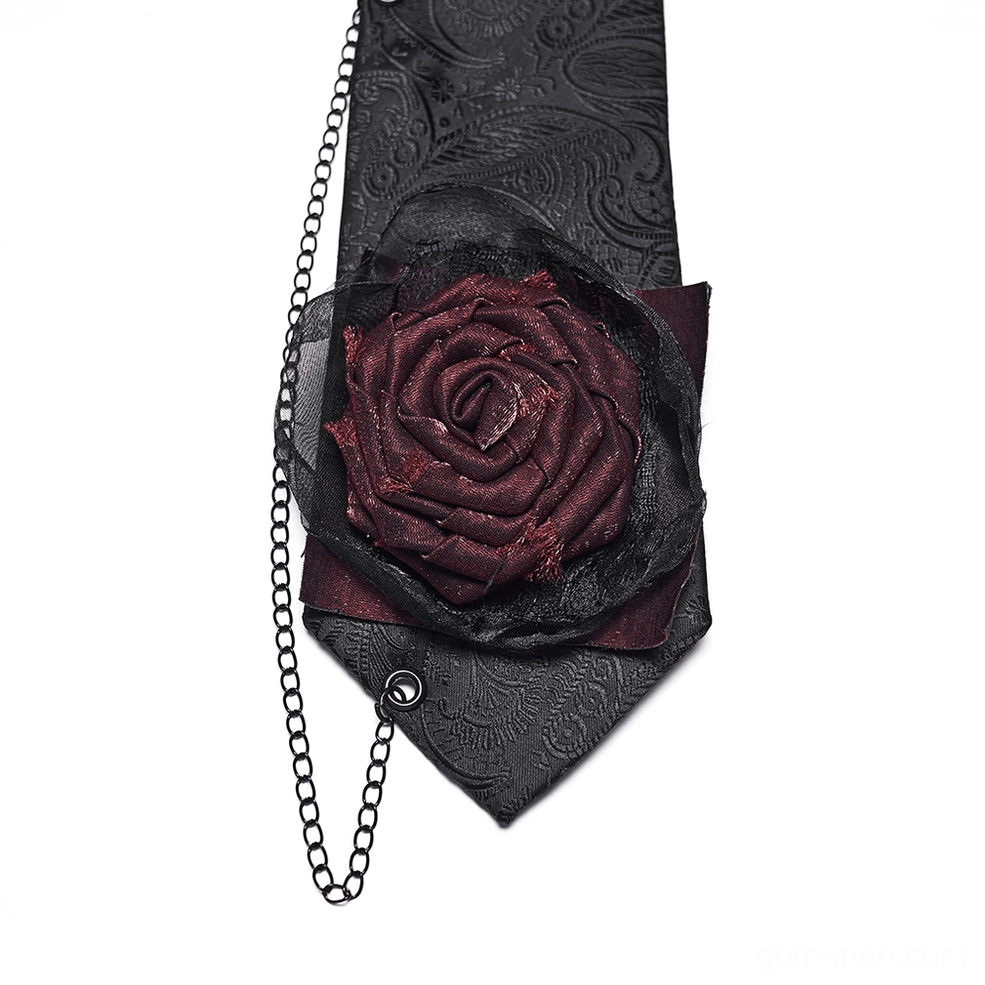 Close-up detail of black paisley gothic necktie showing sheer-trimmed burgundy rose, black metal chain, and jacquard paisley base fabric