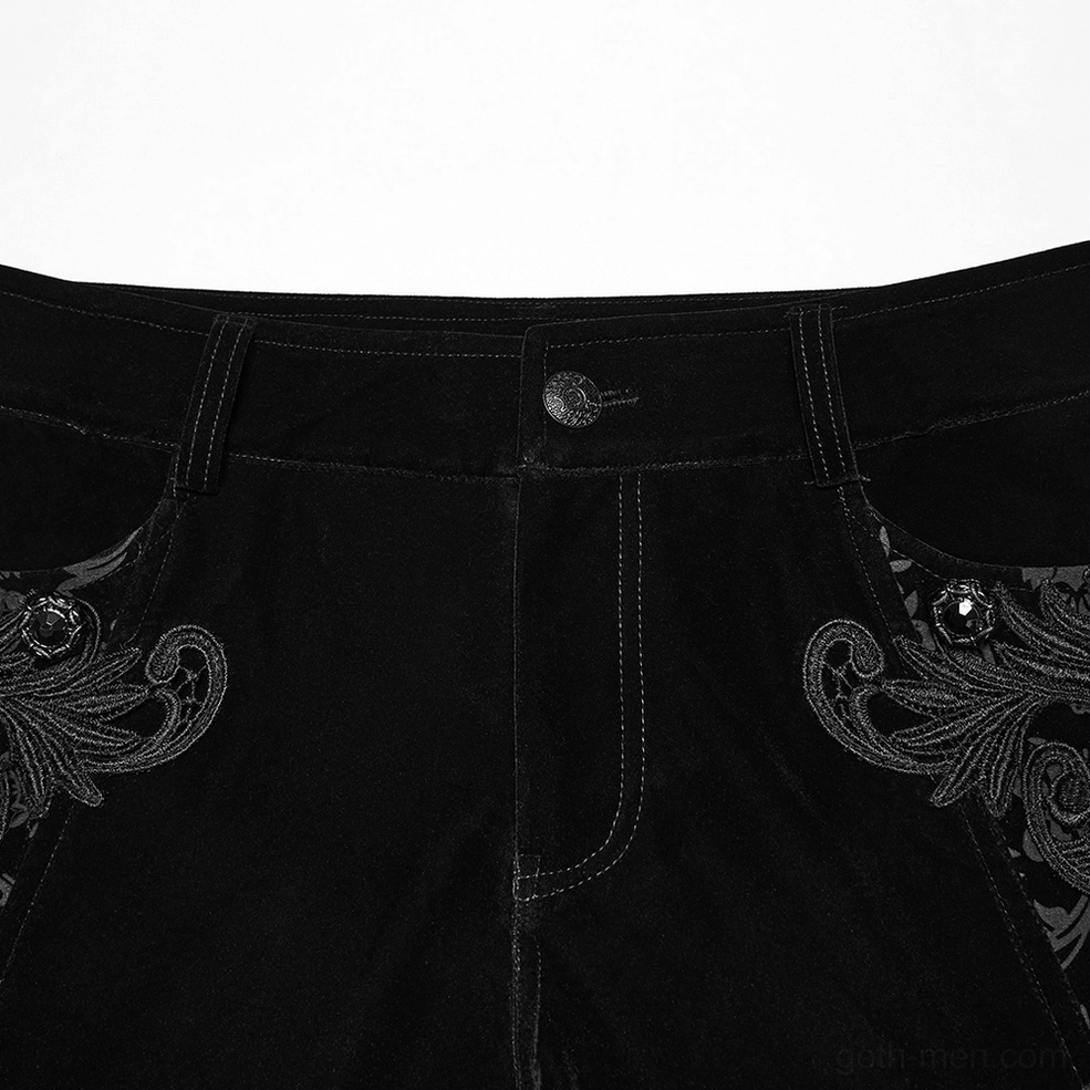 Close-up detail of black velvet gothic pants front waistband showing gemstone button closure and ornate hip embroidery