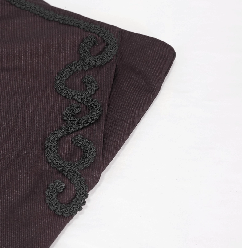 Macro view of delicate black scroll lace trim adorning the side pocket of wine red gothic trousers