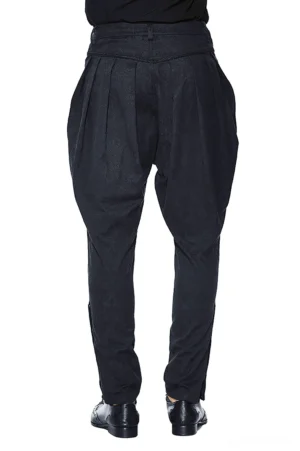 Rear view of black gothic harem trousers on male model showing structured high waistband, pleated back details, and tapered leg silhouette