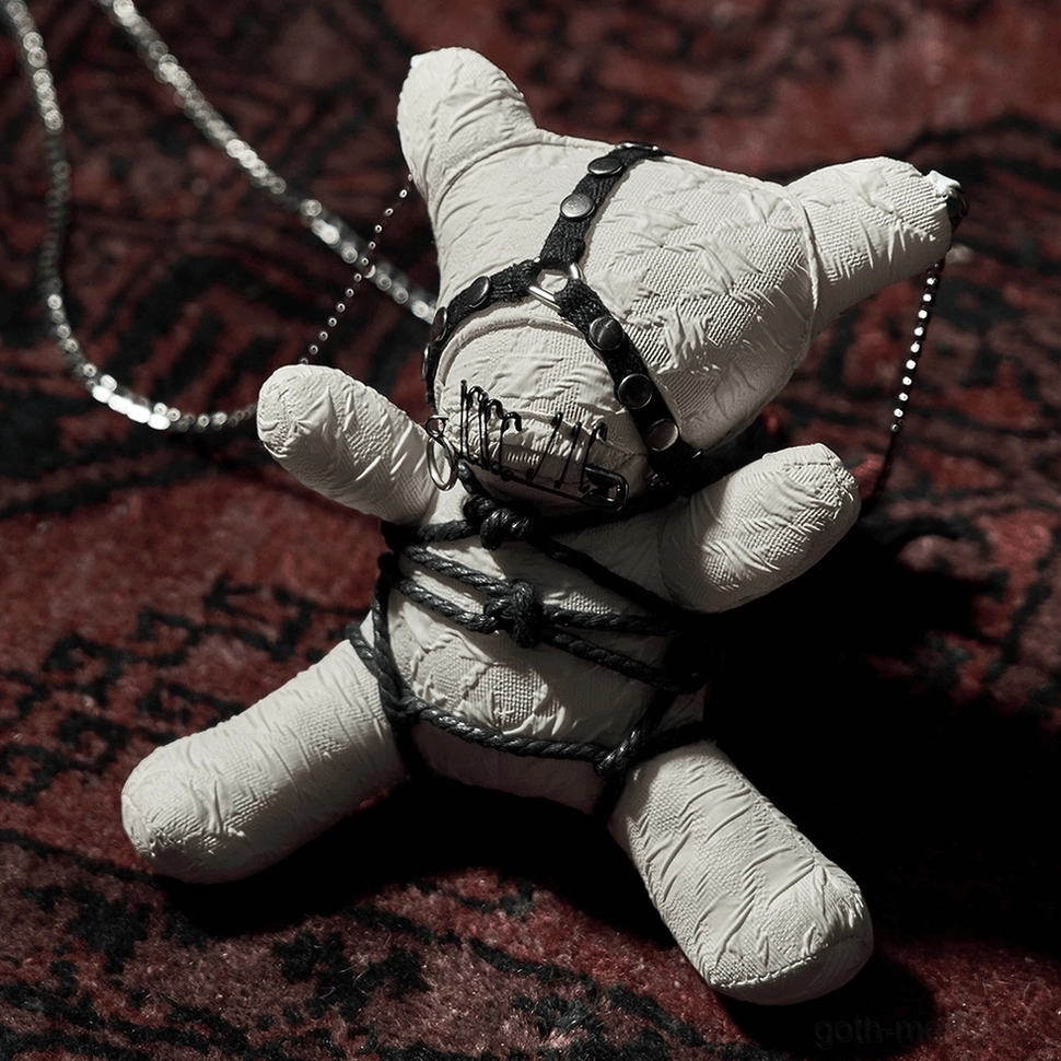 Cream plush ornament with black bondage harness and safety pin accent in three-quarter view