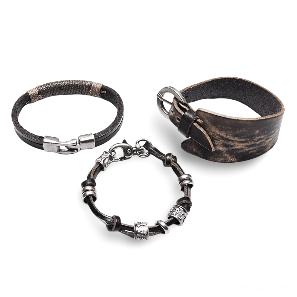 Three-piece dark gothic punk bracelet set overhead view, weathered vintage leather with silver metal details and engraved beads, alternative jewelry collection