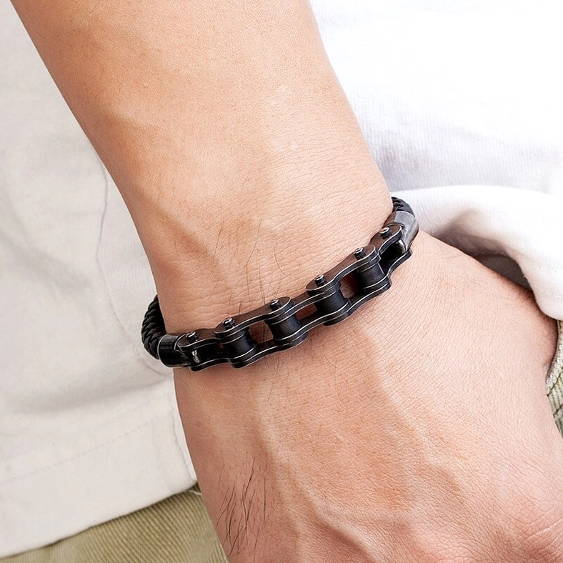Stainless steel chain leather bracelet flat lay on dark stone and fabric backdrop, gothic punk aesthetic styling