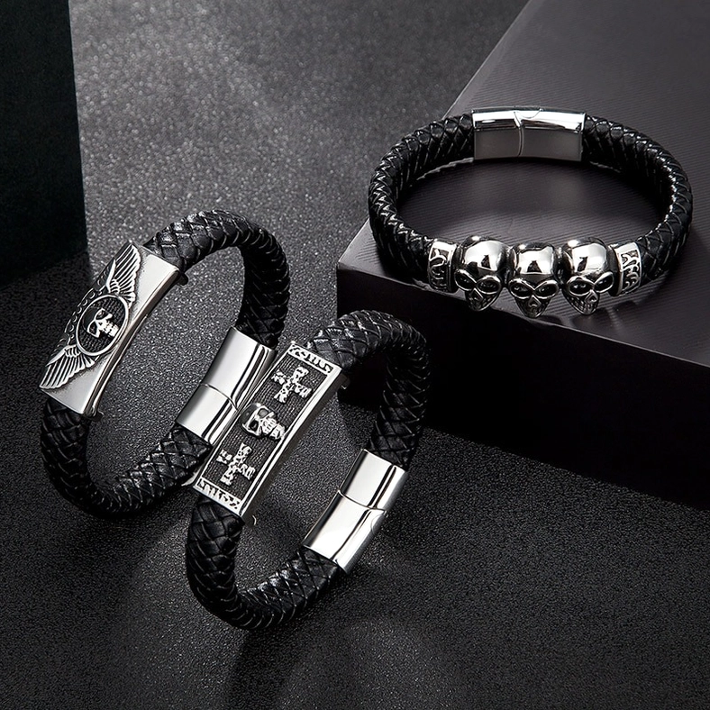 Studio display of gothic leather bracelets featuring cross and winged skull designs in dark aesthetic setting